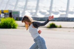 Young woman dancing joyfully on a sunny day in an outdoor setting photo