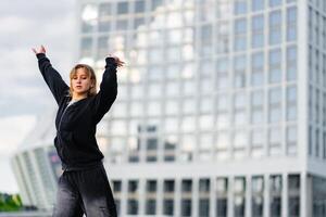 Young dancer performs an expressive routine in an urban setting at dusk photo