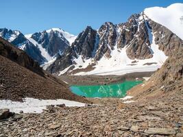 Awesome mountain glacial massif with a lake. Summer mountain camp on the shore of a cold turquoise glacial lake, distant view. Mountaineering camp at the Blue Lake. Aktru mountain range, Altai. photo