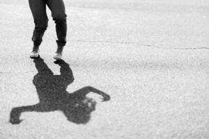 A playful child jumps, creating a whimsical shadow on wet pavement photo