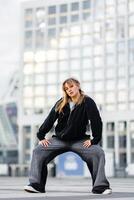 Dancer striking a powerful pose in urban setting on a sunny day photo