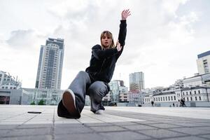 Young dancer performing a dynamic move in an urban setting during the day photo
