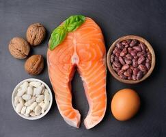 Healthy food. Crude steak of salmon and walnuts , egg top view on black backgrounds photo