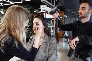 Stylists preparing a model with makeup and hair in a modern salon setting photo
