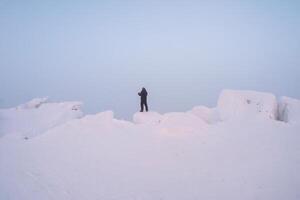 man stands on top of a snowy white mountain photo