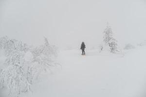 Back view of unrecognizable active person walking on foggy mountains photo