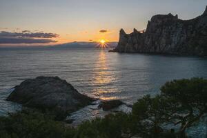 Last rays of the setting sun on the horizon near a cliff. photo