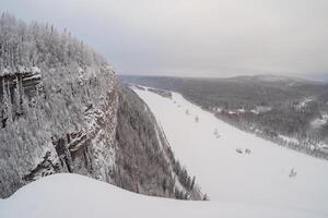 A rocky snow-covered cliff above a frozen river. photo