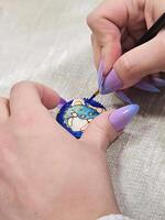 art process of pouring epoxy resin into a wooden toy. Technology process of creating a painting in style resin art, works with epoxy in studio, makes a wooden stand with the image. Close up. photo