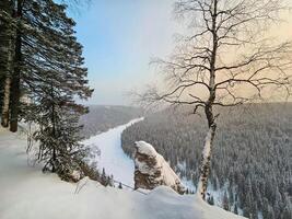 Winter on the Usva pillars. Top view of a frozen river in a snowy wooded rocky canyon. photo