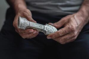 hands of the archiologist hold an ancient silver dagger handle photo