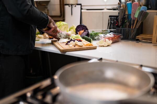 Close up of professional chef preparing ingredients for vegetarian meal in restaurant's kitchen. He is cutting onion.