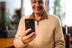 Close up photo of senior man using smart phone while sitting in the city bar. Focus on phone.