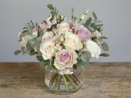 beautiful bouquet of roses and greenery in clear glass vase on wooden table photo