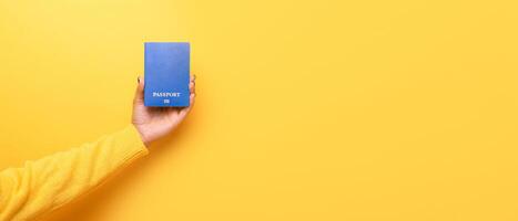 passport in hand over yellow background photo