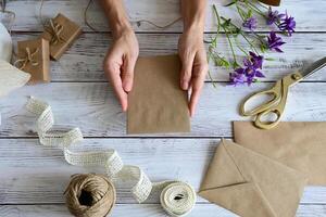 This image features a hand-tied bouquet of white flowers being wrapped with a textured white ribbon. photo
