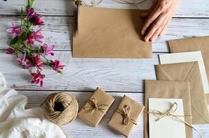 A photograph capturing the process of tying a bouquet of small white flowers using a delicate white lace ribbon, with gold scissors visible nearby on a dark, textured background. photo