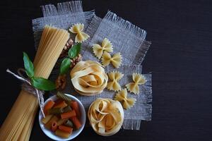 The picture features a selection of ingredients often used in Italian cooking spaghetti tied with a red ribbon, ripe tomatoes, photo