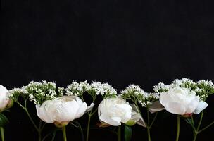 This photograph presents a cluster of white peonies and small white flowers in a simple arrangement. photo
