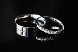 Two wedding rings showing commitment and eternal love are laying on dark background photo