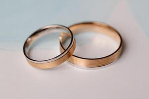 Two wedding rings showing commitment and eternal love are laying on a light blue and white background photo