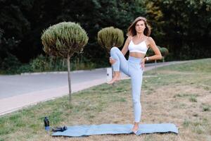 Young woman practicing yoga in a park, holding balancing pose photo