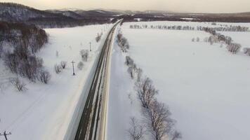 Drones camera show cars on traffic during snow. In background fields, roads. video