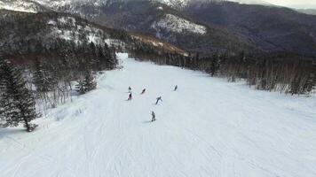 Drone view of a group of snowboarders descending the ski slopes. video