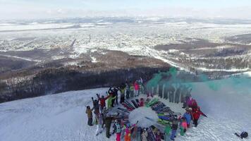 Drone view on a snowboarders on the top winter mountain with green smoke bomb video