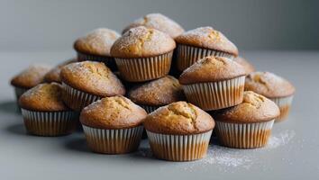 Freshly Baked Muffins Piled Together on a Light Gray Surface with Sugar Dusting on Top.Freshly Baked Muffins Piled Together on a Light Gray Surface with Sugar Dusting on Top. photo