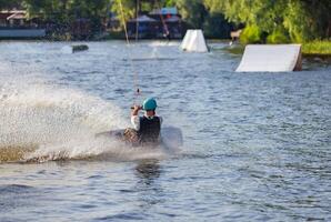 A wakeboarder rushes across the surface of the water at high speed, creating a pile of splashes behind him. photo