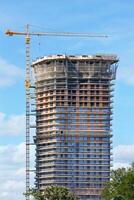 Modern construction of a multi-storey skyscraper with a tower crane on a summer day. photo