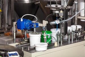 Mechanism for seaming and packing products into plastic buckets on a production line in the food industry. photo