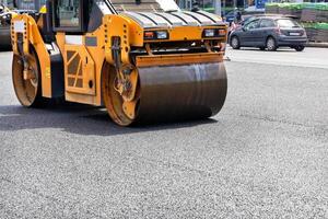 The vibrating roller rams and compacts the fresh asphalt in the middle of the carriageway on the road. photo