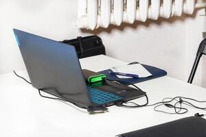 Workplace with a laptop, a power bank, a notepad and a pen on a light background. photo