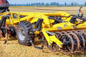 Hitch of a powerful multi-row disc harrow with a tractor on the background of an agricultural field. photo