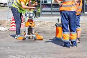 Road workers use a core drilling machine to take cores from an asphalt pavement during road repairs. photo