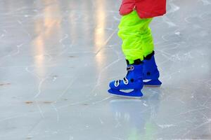 The child learns to skate and stands uncertainly on the ice. photo