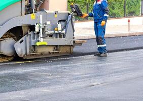 A fragment of the work of an asphalt paver operator on a town road on a summer day. photo