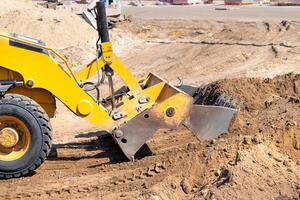 The hydraulic mechanism of the metal bucket of a wheeled bulldozer at the work site. photo