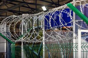 Iron fence with barbed wire and a light element, no entry. Protection of the territory and counteraction to illegal entry. photo
