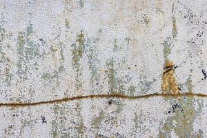 Old metal sheet with cracked paint and a rusty traced curve. photo