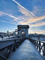 A fragment of the Szechenyi Chain Bridge over the Danube River in the early morning against a blue sky, photo