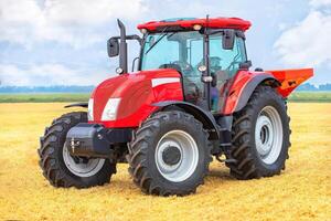 Powerful red tractor in vast wheat field under blue sky, showcasing modern agricultural machinery concept photo