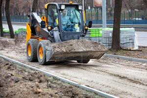 Skid steer loader moving soil, construction site machinery, urban development, dirt transportation, heavy equipment construction concept. photo