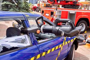 Emergency response demonstration using tools on a blue vehicle in a city setting photo