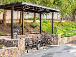 Elegant benches under a stylish canopy in a serene park setting during midday photo
