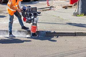 Construction worker using equipment to break concrete on a sunny day. Copy space. photo