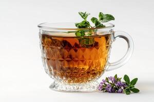 Glass teacup with fresh oregano and blooming sage on white background photo