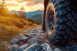 Off-road vehicle standing on rocky terrain at sunset with mountains in background. photo